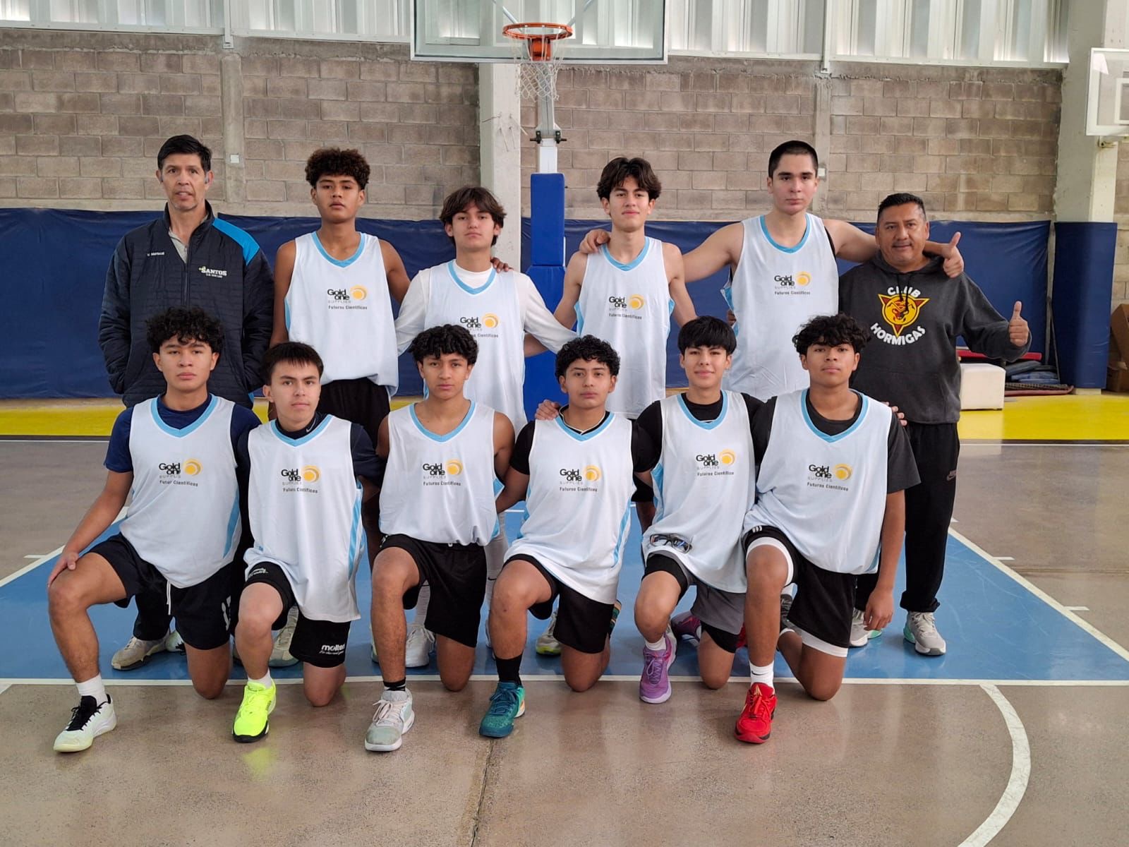 Equipo de básquetbol "Los futuros científicos" posando con sus uniformes patrocinados por Gold One en una cancha deportiva.